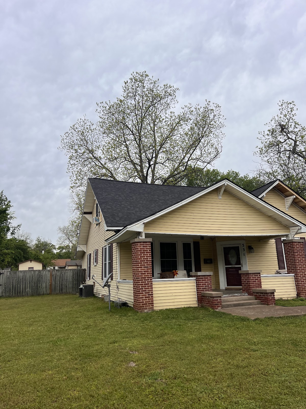 Completed black shingle roof on a yellow Craftsman bungalow